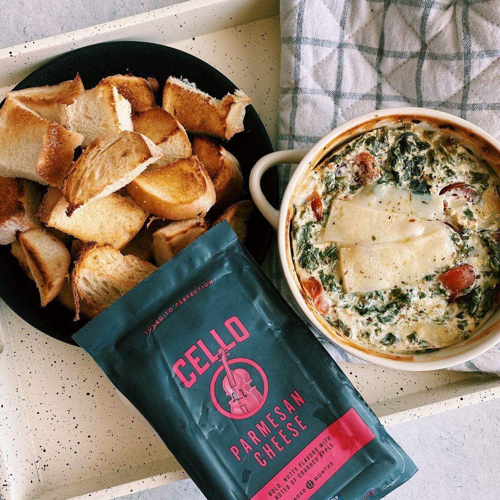 Flat lay of toasted bread with Healthier Hot Spinach Dip and full block of cheese