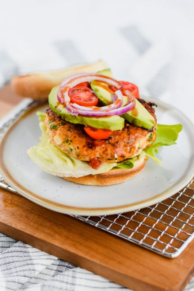 assembled chicken burgers topped with avocado, tomato, and red onion and a toasted bun
