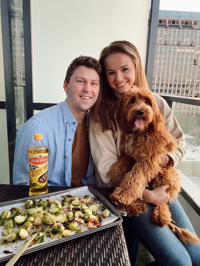 couple holding shaggy dog on a patio with grilled dinner in front of them
