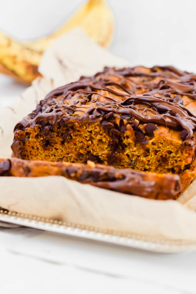 close up image of pumpkin banana bread loaf with one slice cut off