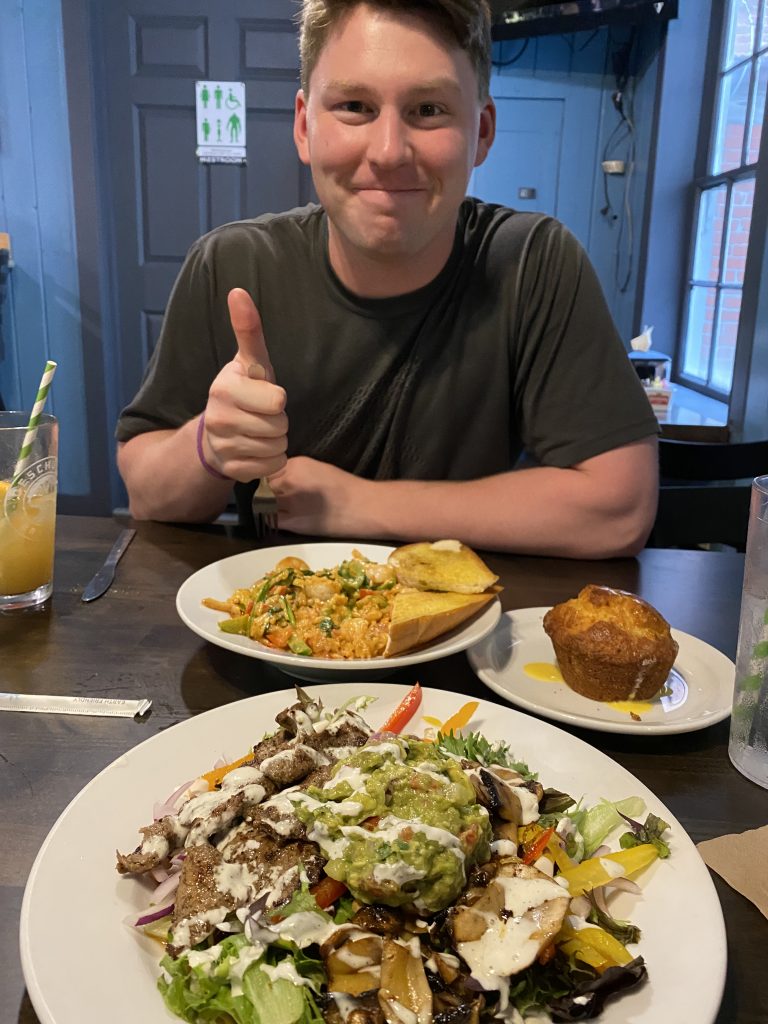 man holding a thumbs up after full plates of food were delivered to table to eat