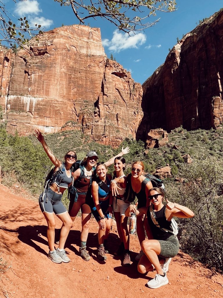 group of six ladies smiling in front of a large mountain in Zion National Park