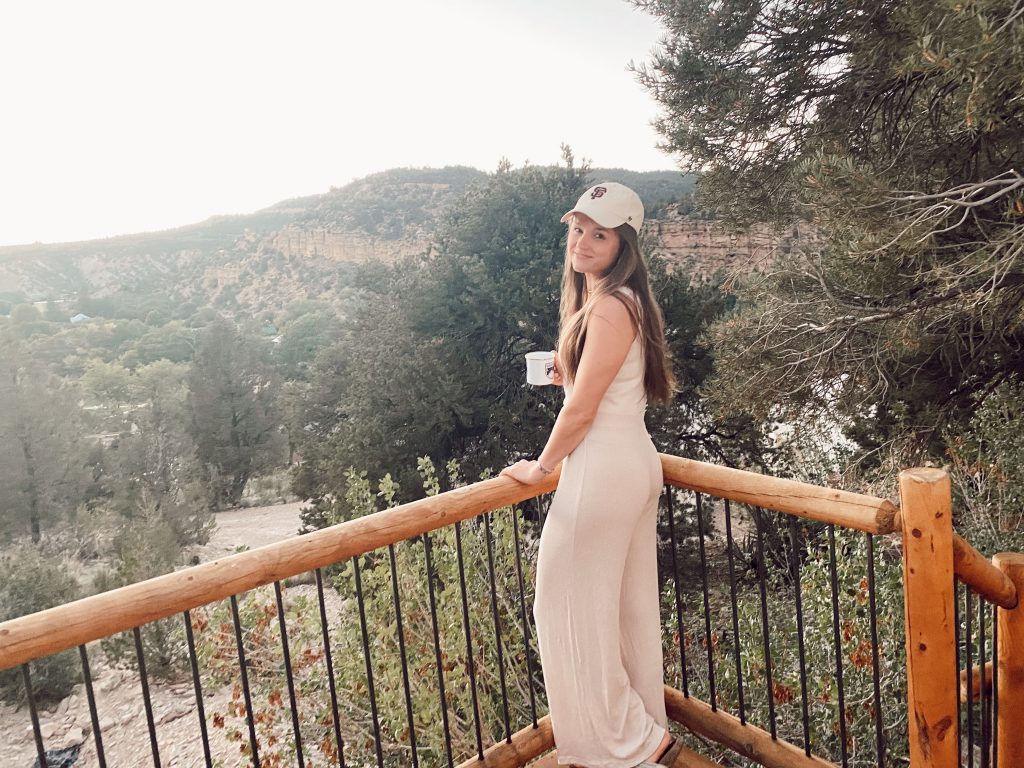 girl standing with mug on a balcony overlooking the mountains