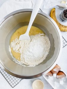 rubber spatula pouring flour into wet ingredients