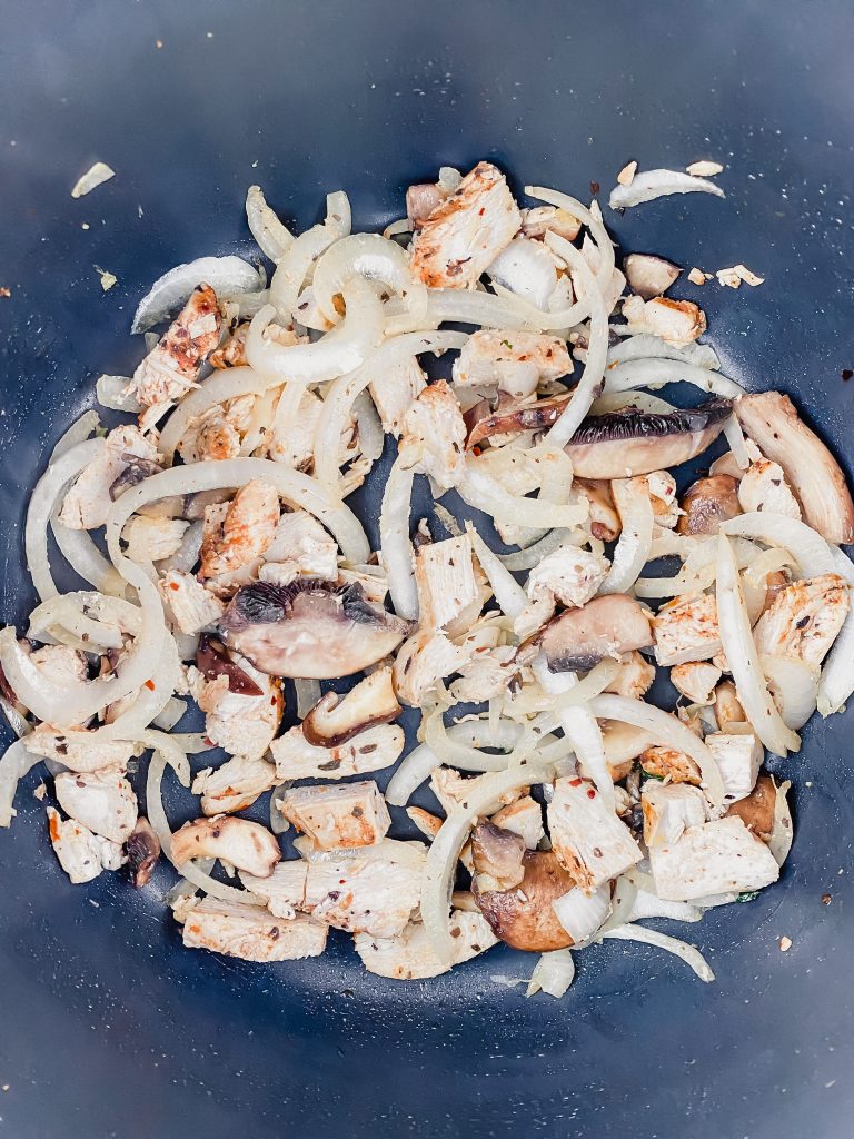 sauteing onions, chicken, and mushrooms in a stove pot