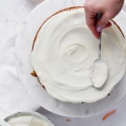 Icing a carrot cake with cream cheese frosting