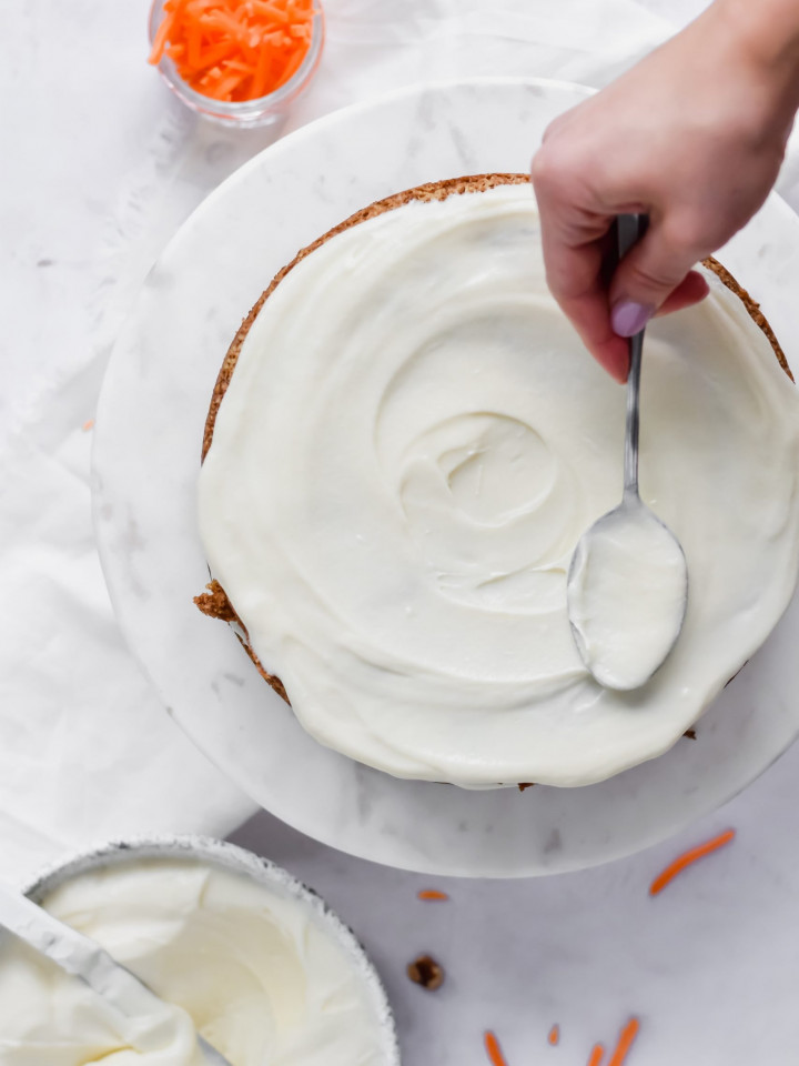 Icing a carrot cake with cream cheese frosting.
