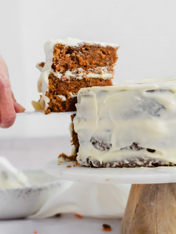 Cutting a slice of carrot cake with cream cheese frosting