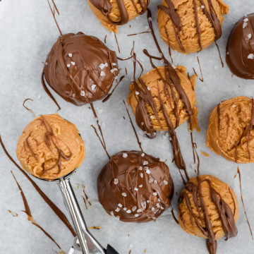 Scooping peanut butter on a tray of chocolate peanut butter truffles