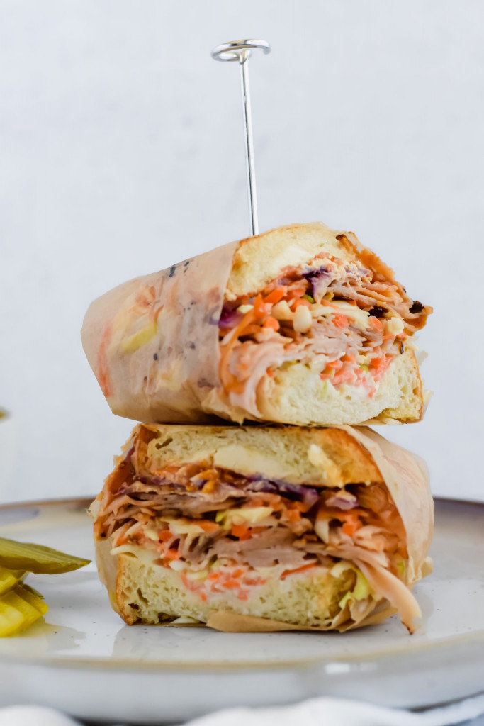 Two halves of a wrapped Grilled Turkey Reuben Sandwich stacked on top of each other.