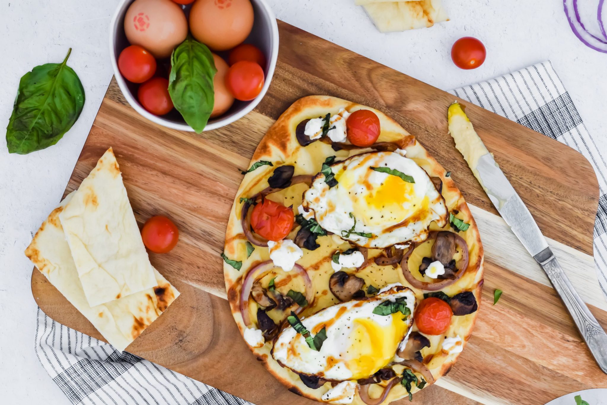 Savory Breakfast Flatbread with hummus, fried eggs, vegetables, goat cheese and balsamic glaze