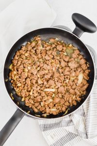 Ground spicy sausage and white onion cooking in pan