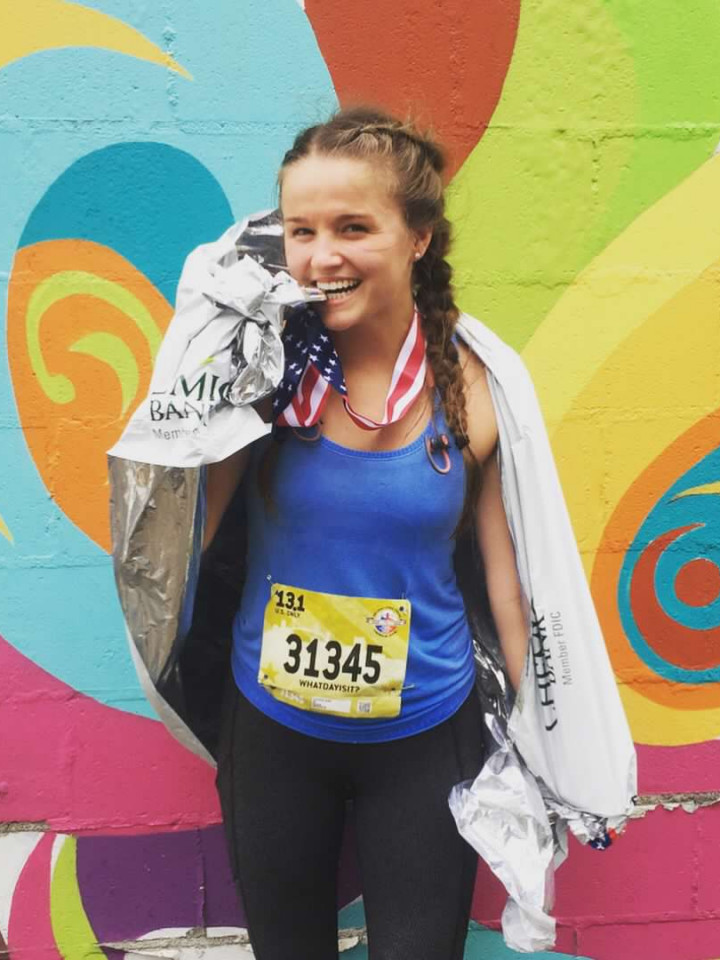 courtney after finishing half marathon race with medal on and colorful background