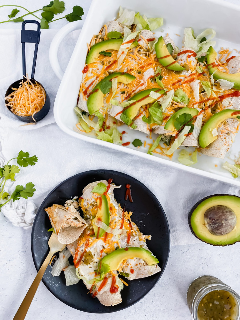 Skinny Turkey Enchiladas in a casserole dish and on a plate topped with sriracha and avocado