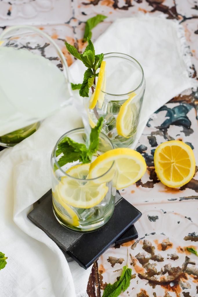 Two glasses garnished with mint leaves and lemon slices