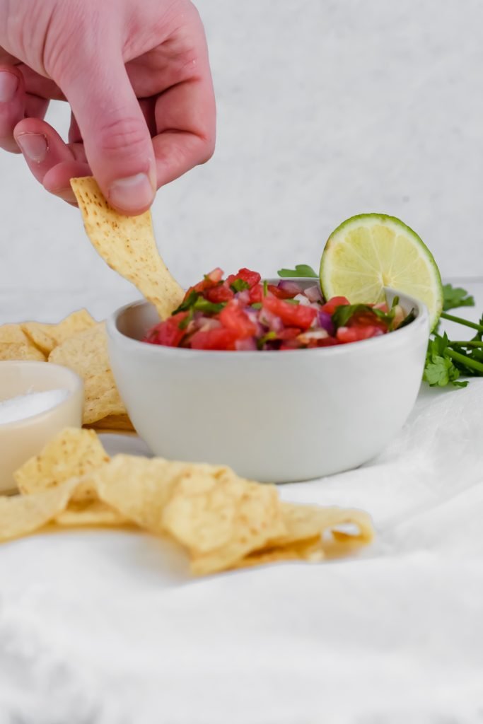 Bowl of Pico de Gallo with a slice of lime and tortilla chips