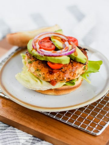 assembled chicken burger topped with avocado, tomato, and red onion and a toasted bun