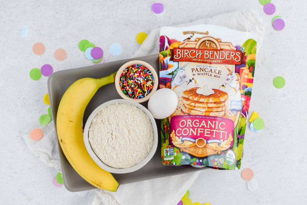 overhead image of ingredients needed: funfetti pancake mix, egg, banana, sprinkles and water