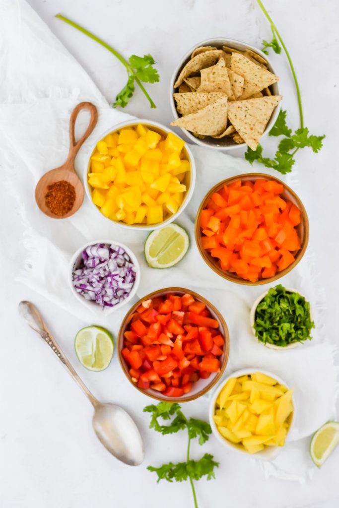 all salsa ingredients separated in bowls on white backdrop
