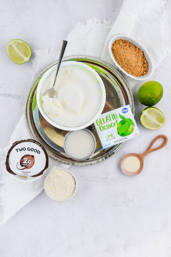 Ingredients for Key Lime Pie Milkshake including yogurt, Cool Whip, lime gelatin, fresh lime, almond milk, xantham gum, and crumbled graham cracker