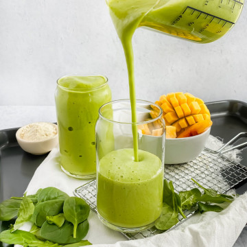 green smoothie being poured into glass cup