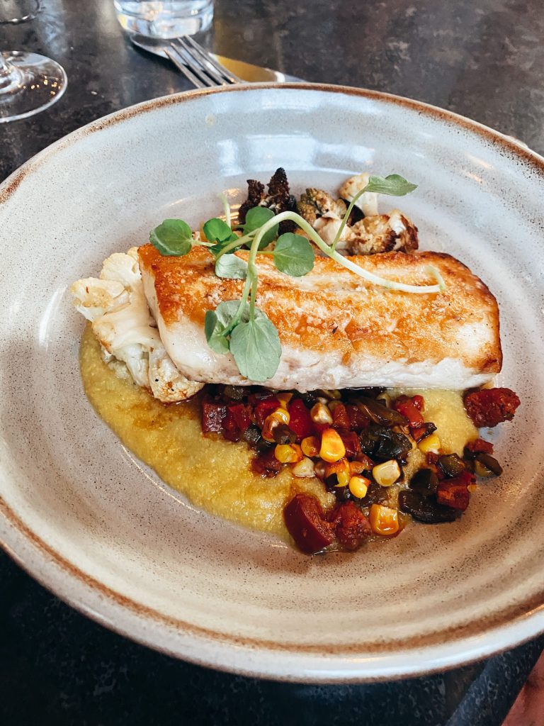 grilled seabass on top of bed of corn polenta and vegetables