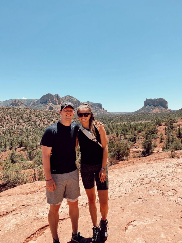 couple in workout clothes smiling in front of backdrop of Sedona, AZ