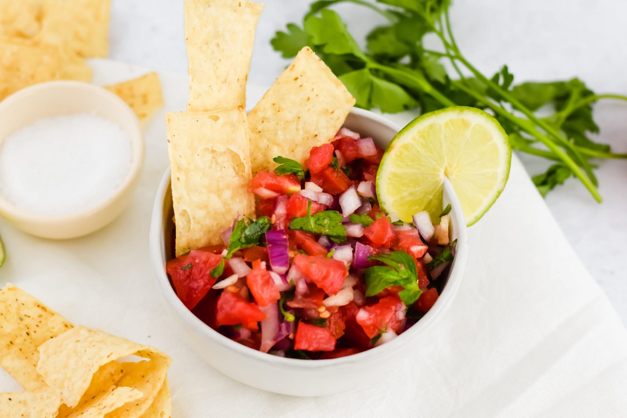 bowl of pico de gallo with fresh cilantro with chips on concrete background