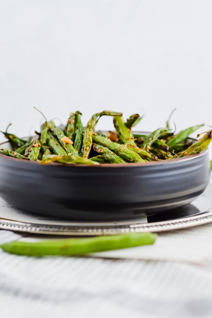 90 degree angle photography of black bowl with green beans cooked inside of them