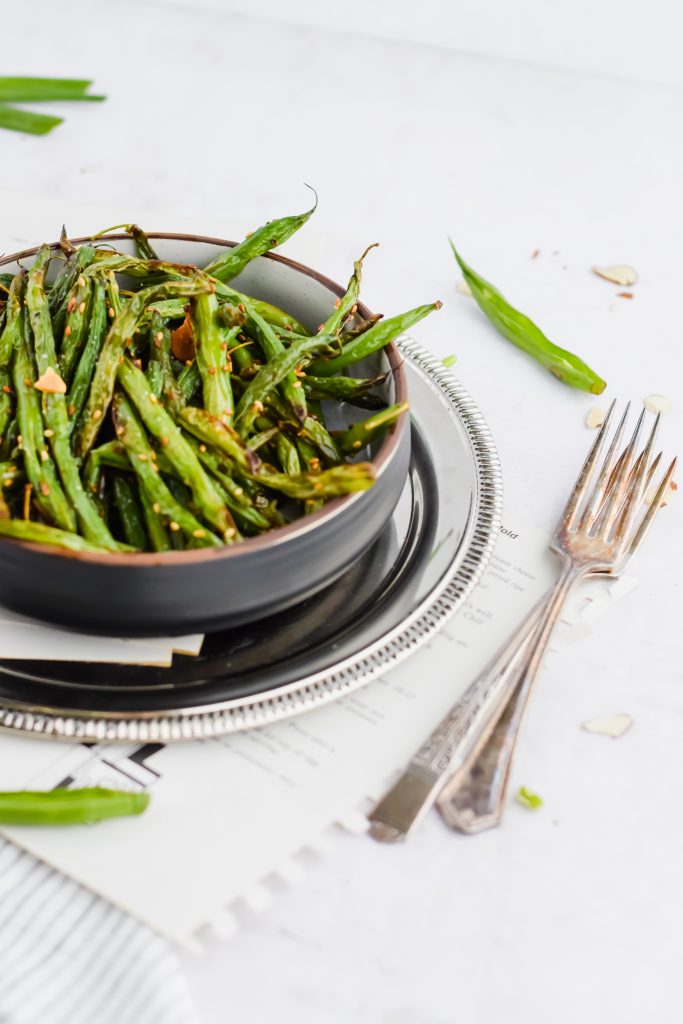 green beans roasted with shaved almonds on top and garnished with balsamic