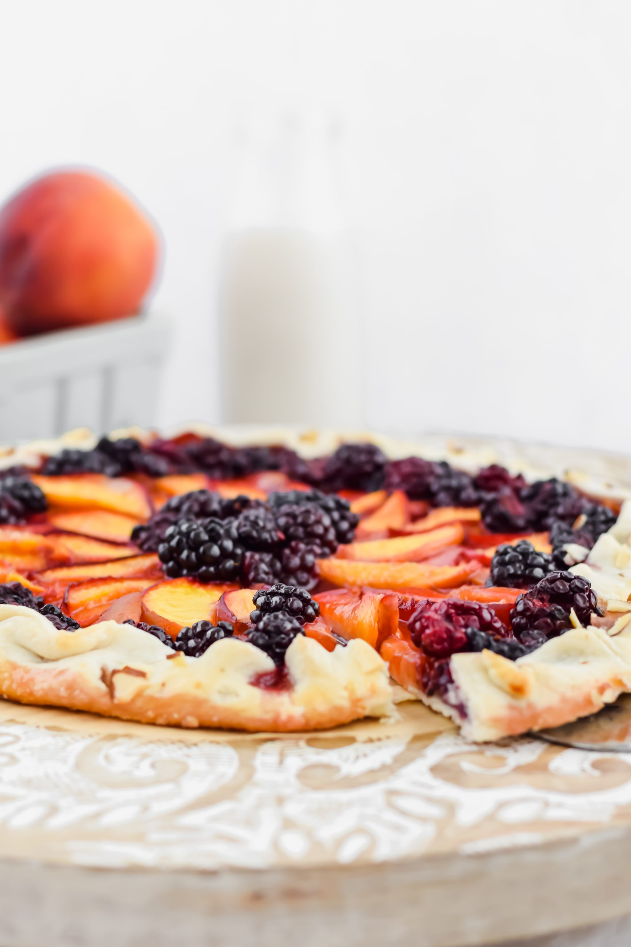 peach blackberry galette after baking with a pie server pulling out once slice