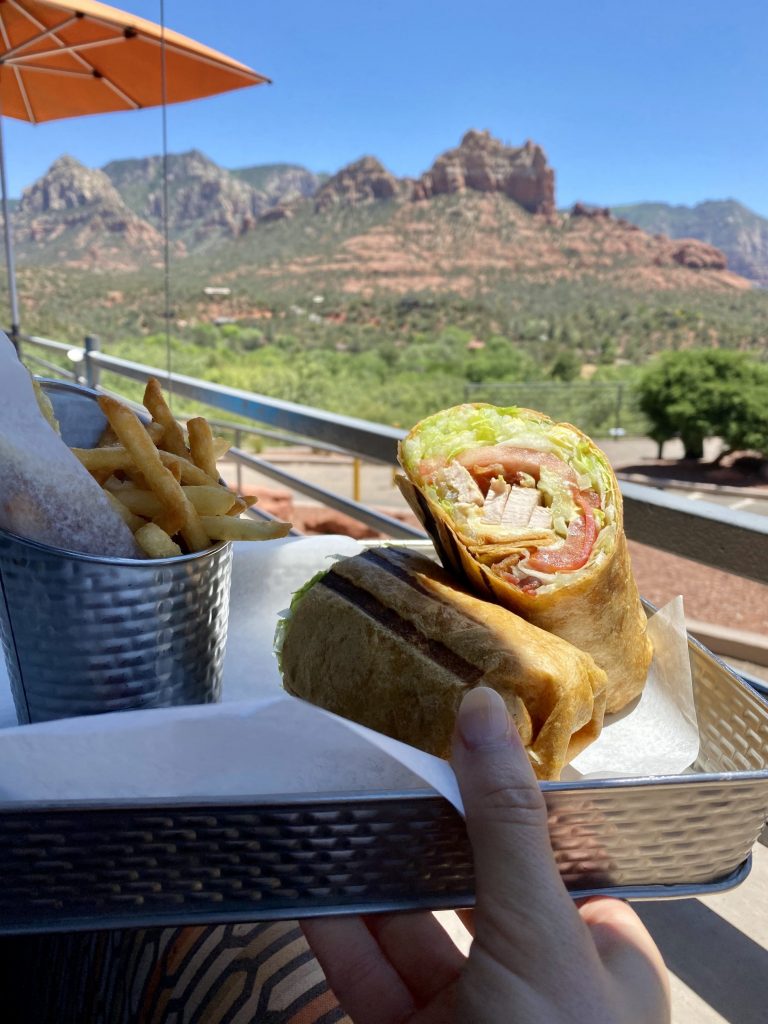 Chicken club wrap with fries on a metal tray with backdrop of Sedona mountains