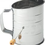 metal flour sifter with wooden knob with white background