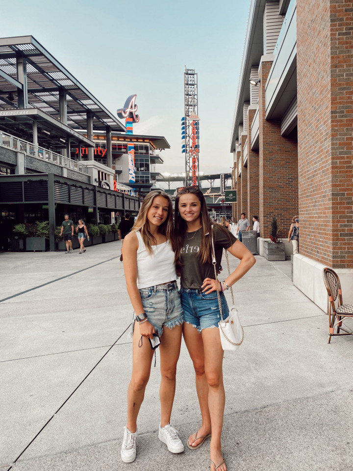two girls standing in front of baseball stadium entrance