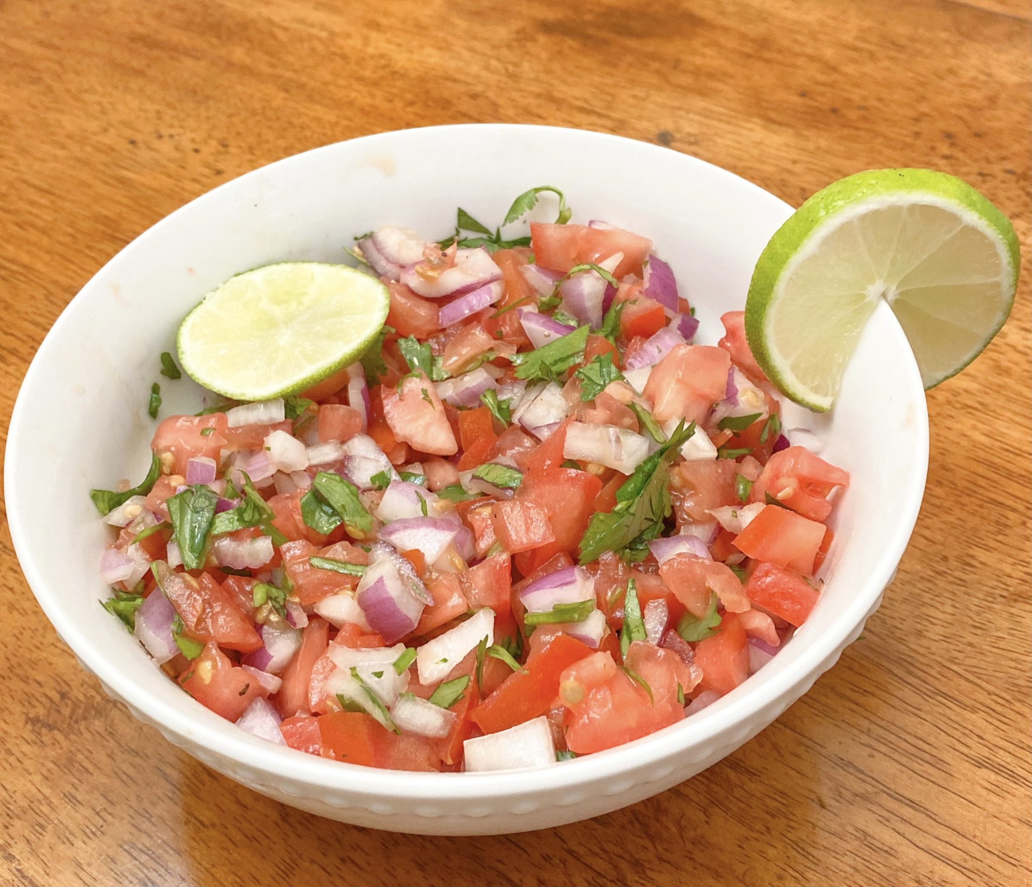 white bowl filled with homemade pico de gallo topped with lime