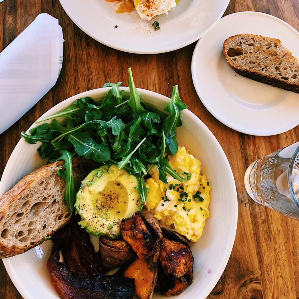 delicious brunch bowl with eggs, toast, sausage, and greens