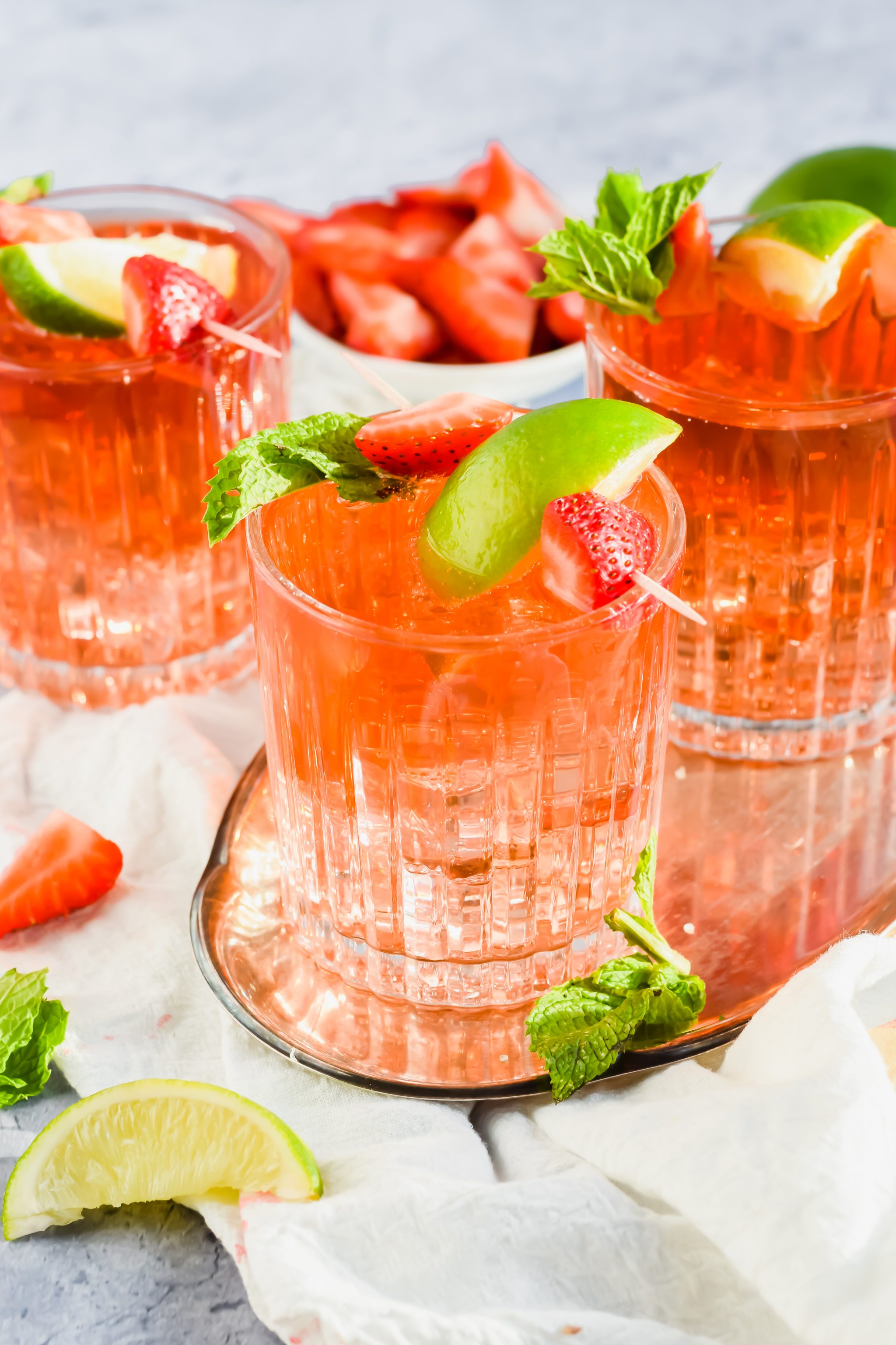 filled cocktail glasses with Caribbean Rum Punch topped with fresh mint, strawberries, and lime