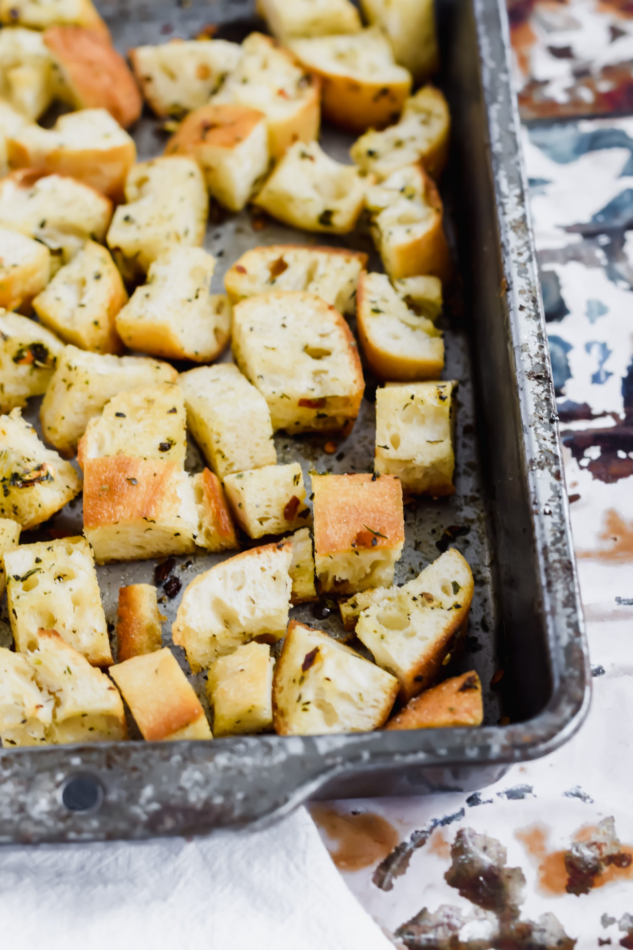 metal sheet pan with toasted homemade croutons on antique tile in the background