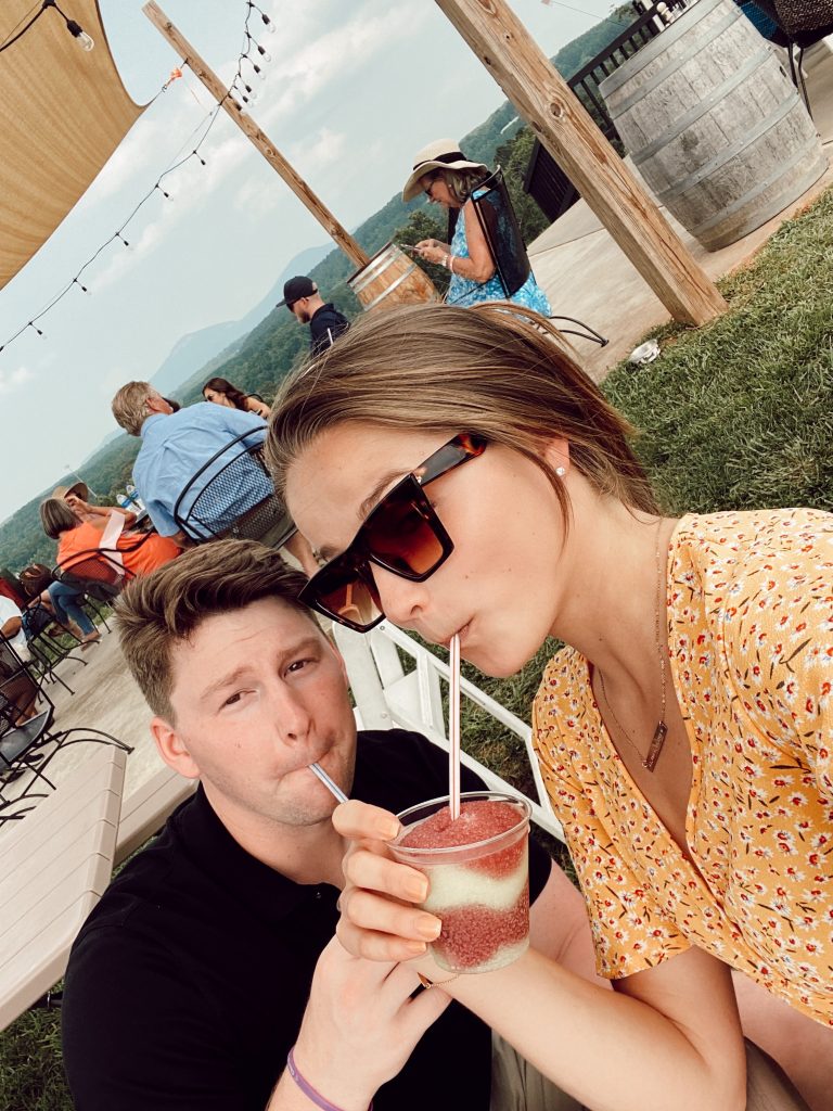 selfie of guy and girl sipping wine slushies making funny faces