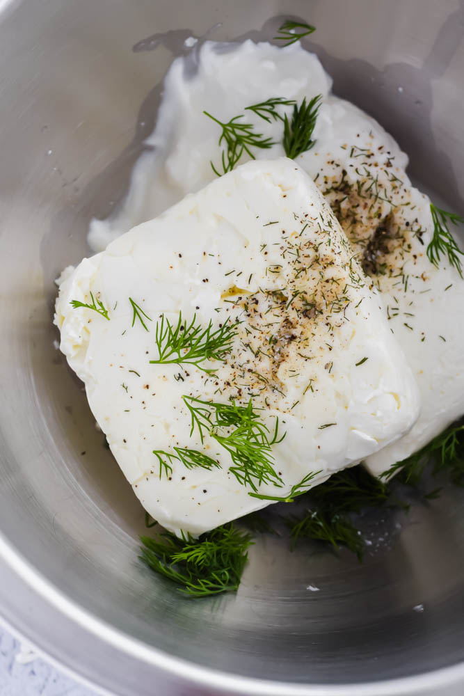 block of feta cheese and cream cheese topped with herbs and seasonings