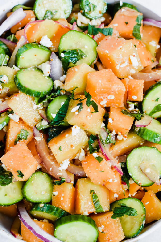 close up image of cantaloupe cucumber feta mint salad all tossed together and fresh pepper on top