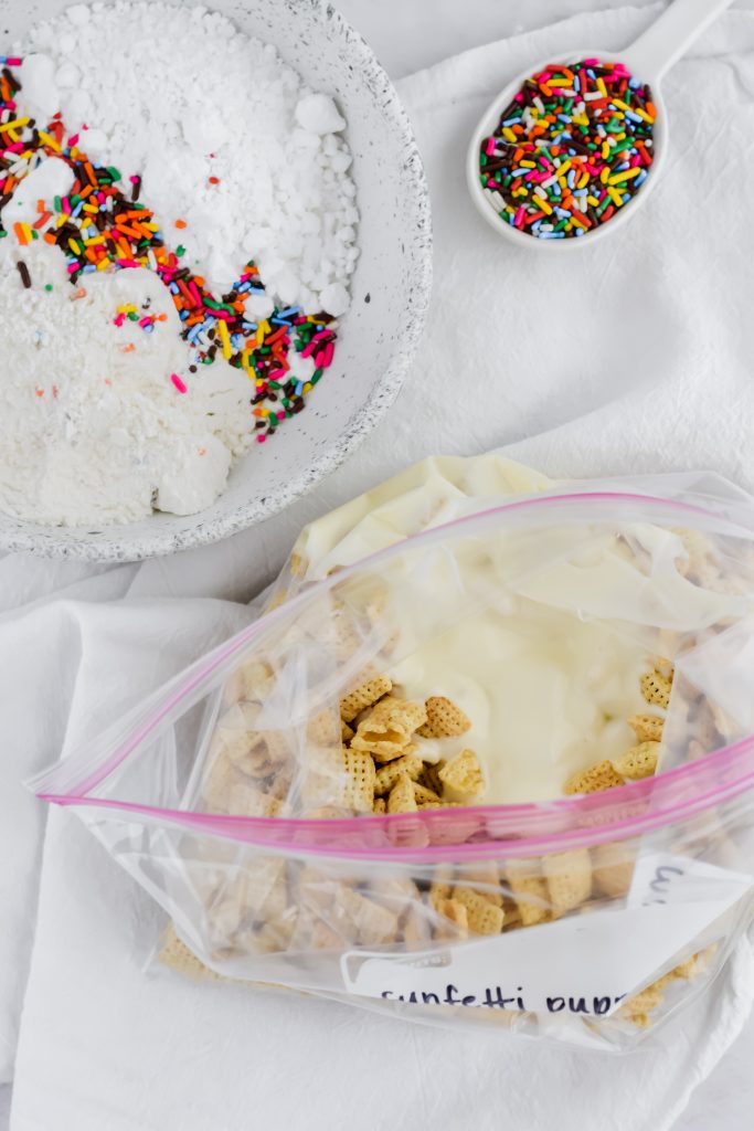 chex cereal with melted lemon white chocolate mixture in plastic bag and cake mix and sprinkles on the side