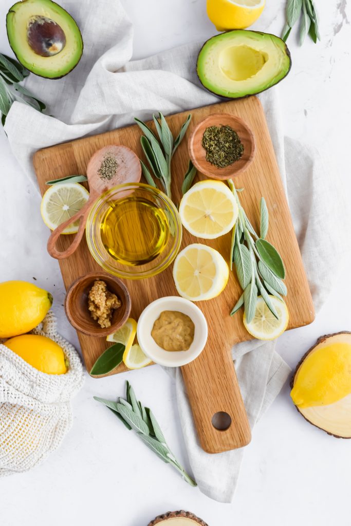 wooden board with each ingredient needed in homemade lemon vinaigrette dressing on white background