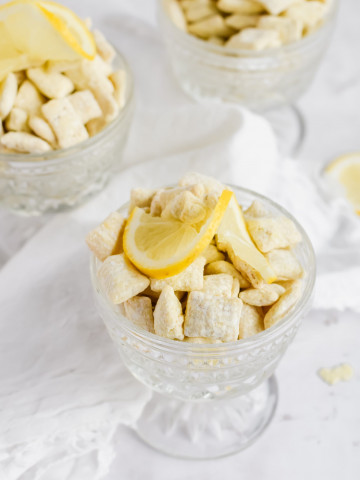 three glasses of lemon puppy chow topped with slices of lemon