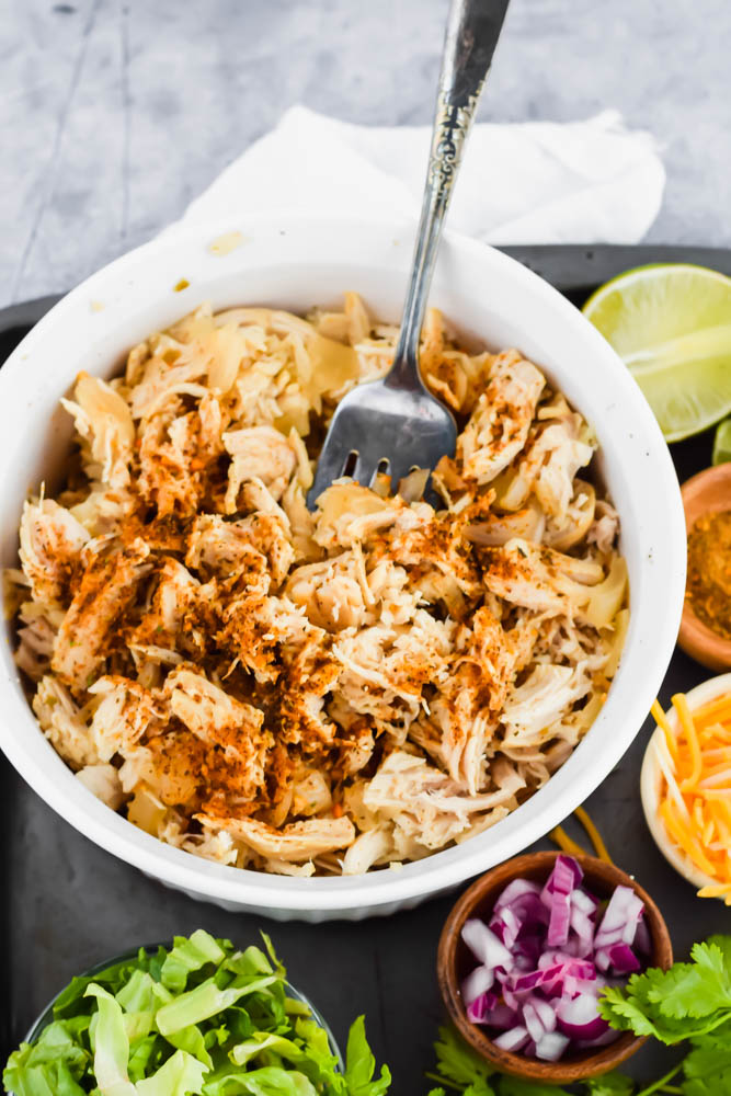 white ceramic bowl filled with pulled chicken and fork scooping out some