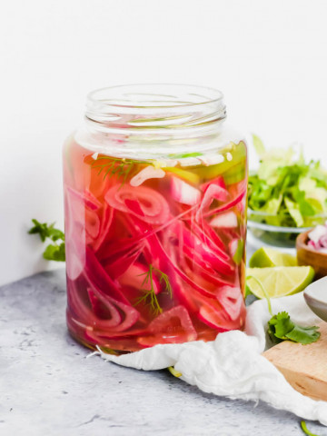 apple cider vinegar pickled onions in mason jar with jalapeños and herbs.