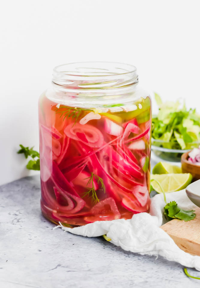 apple cider vinegar pickled onions in mason jar with jalapeños and herbs.