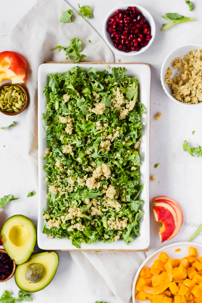 kale salad base topped with quinoa and other ingredients surrounding it