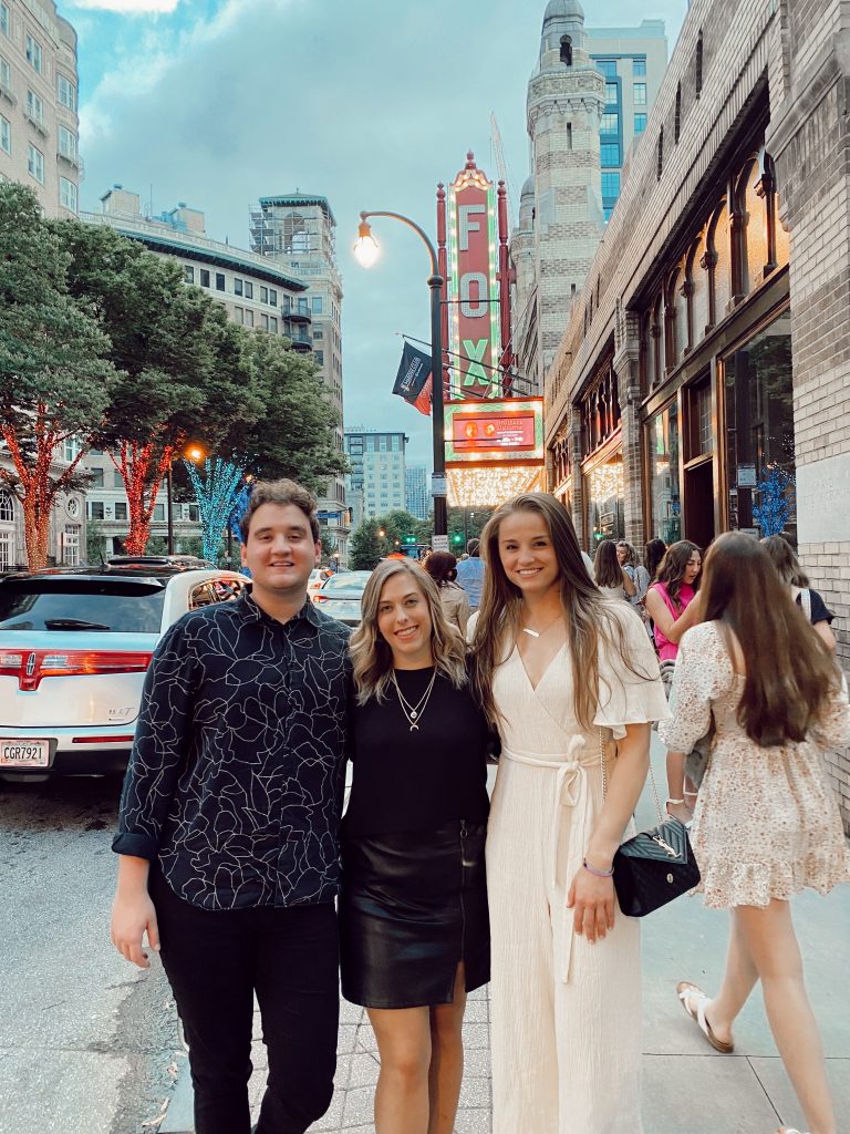 a guy and two girls standing in front of the Fox theatre dressed up