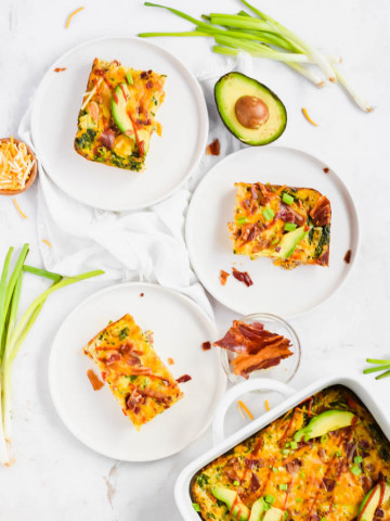 three white plates filled with bacon sweet potato and egg casserole slices and garnished with green onions and avocado